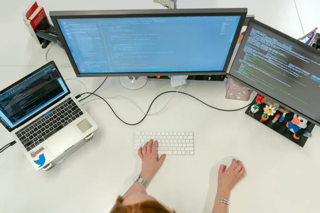 Data Scientist typing on laptop and desktop
